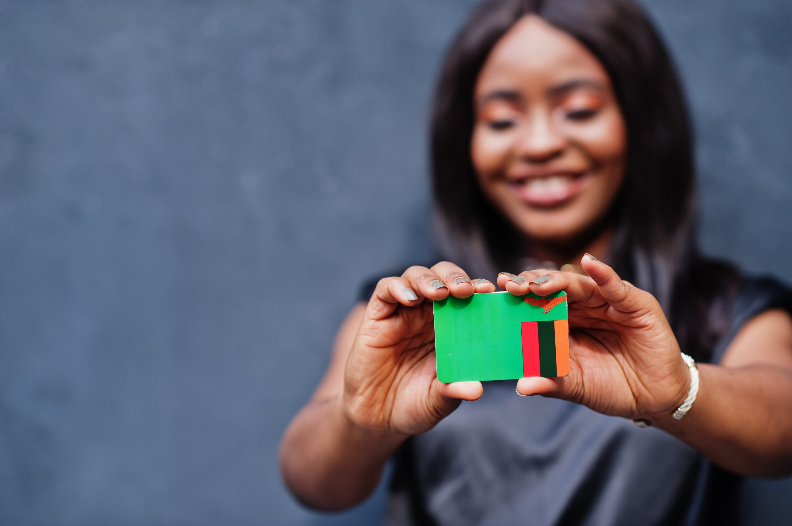 african woman hold small zambia flag in hands.